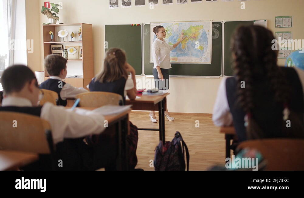Female teacher in class near the map of the world communicates with ...