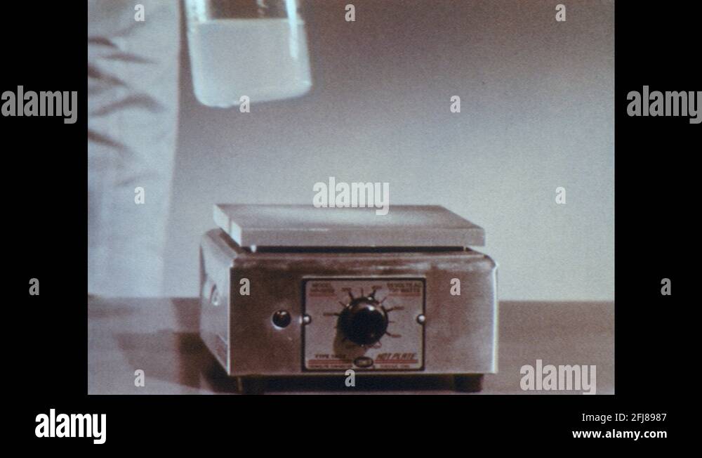 1960s Lab. Hand puts beaker on hot plate. Text reads "35 NITROGEN