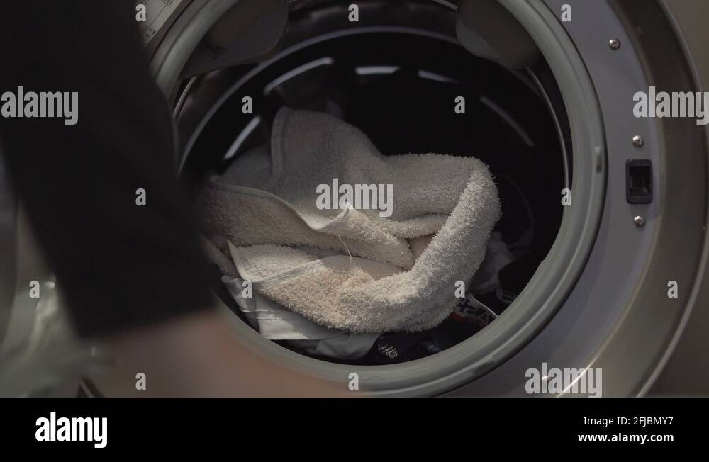 Woman empties the washing machine from her clean clothes after washing