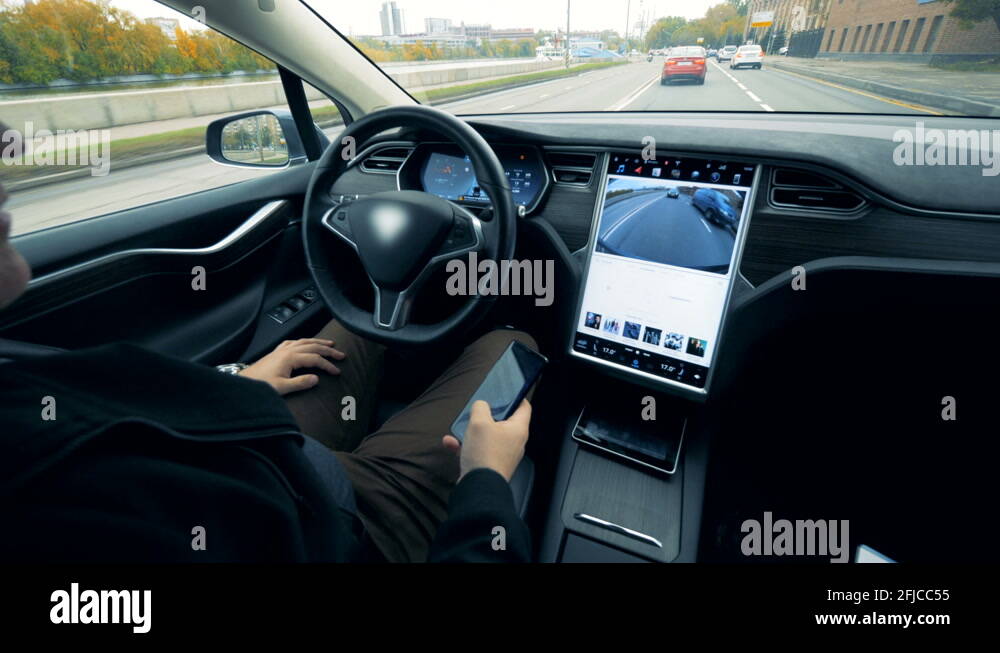 Man sits in an electric car going on autopilot. Futuristic automated