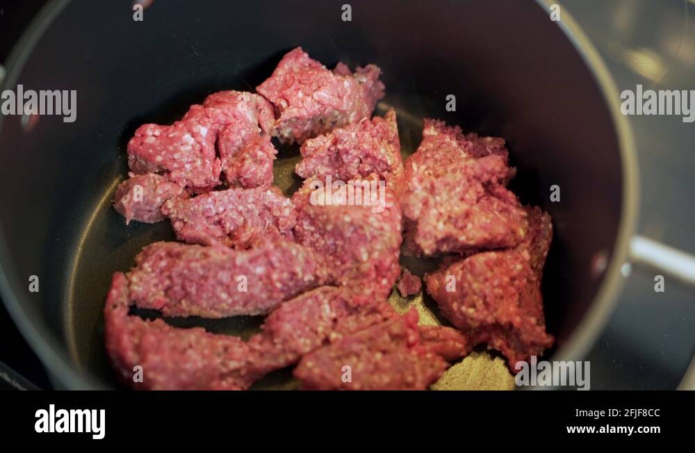 Ground beef mince cooking in black pot with occasional stirring and lid