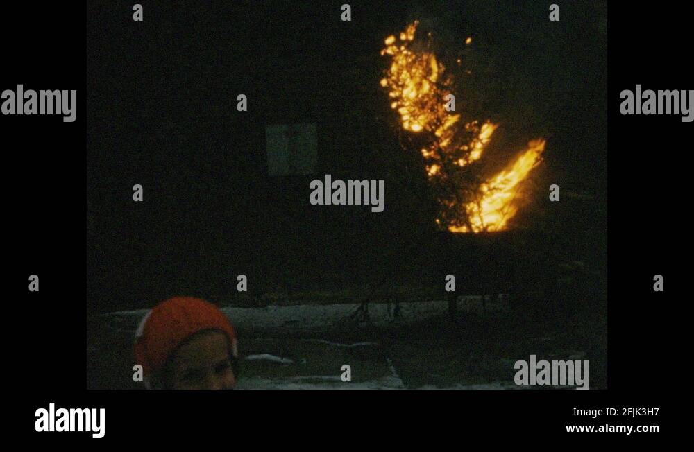 1950s Little girl watches tree burn in trash can. Little girl runs