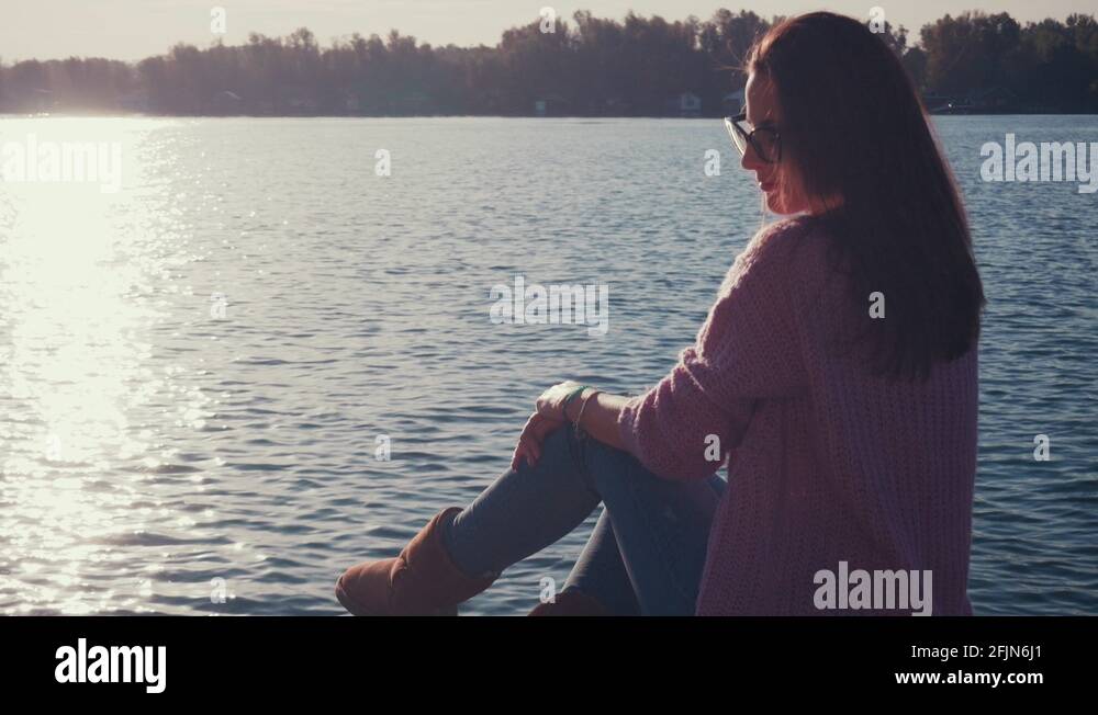 Girl sitting alone on the river pier with sad expression Stock Video ...