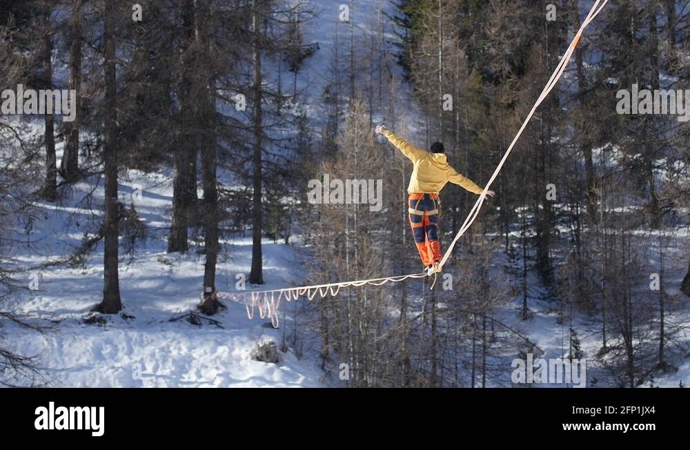 highliner walking and balancing on highline over the snow of a ski ...