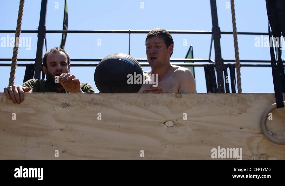 Two Muscular Male Athletes Throwing a Weighted Medicine Ball and