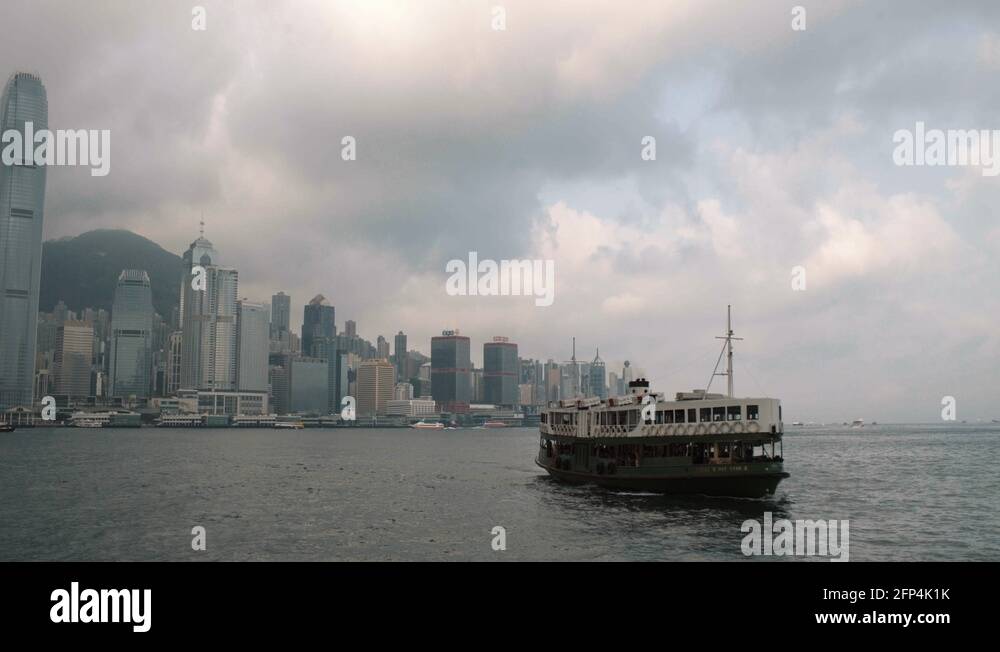 Ferry cruising in Victoria harbour during cloudy morning with Hong Kong ...