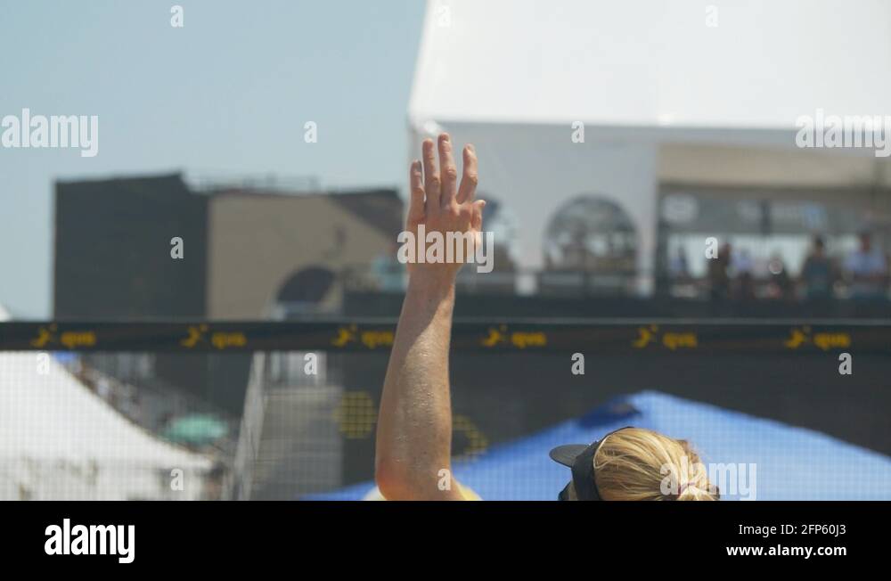 Women serve serving while playing pro beach volleyball in the sand