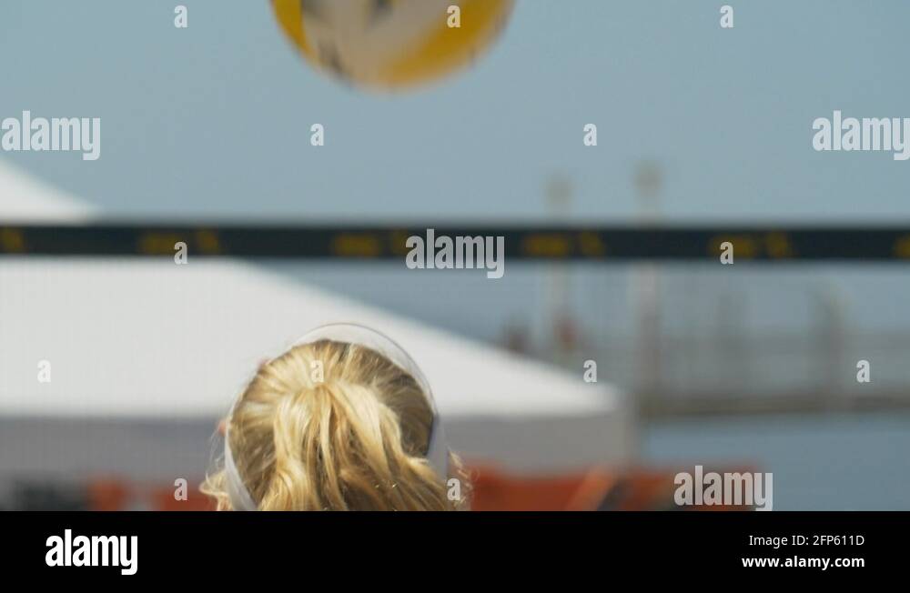 Women serve serving while playing pro beach volleyball in the sand