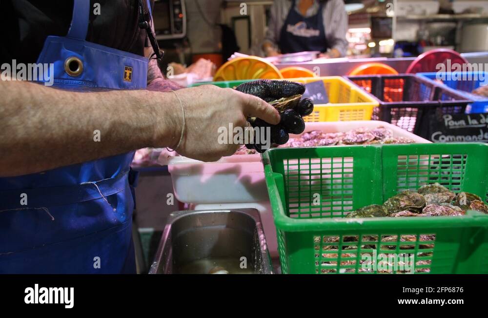 Oyster farmer opening oyster shells in a fish market Sete France