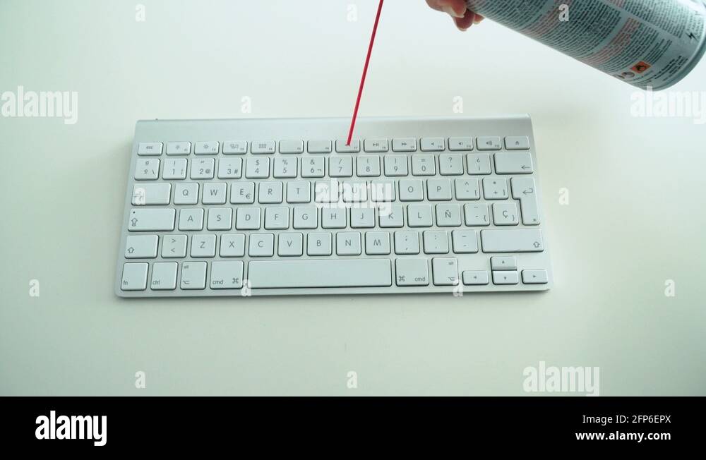 Dusting white keyboard with compressed air spray, White Background