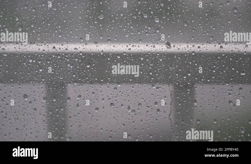 Raindrops Dripping On The Surface of Glass Window on blury background