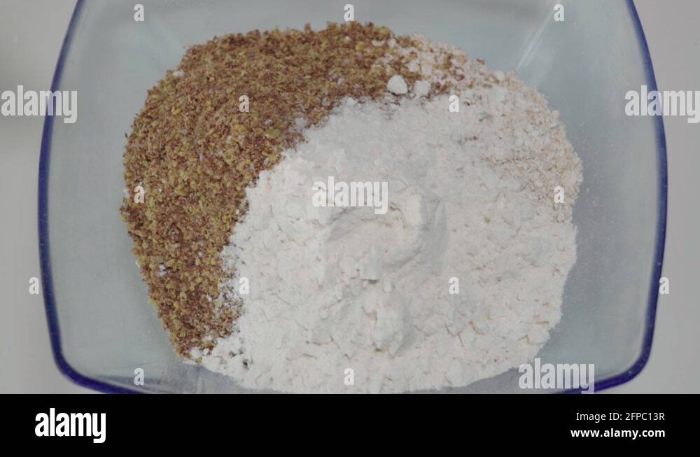 Adding teaspoon of baking soda to flour and flax mixture in glass bowl