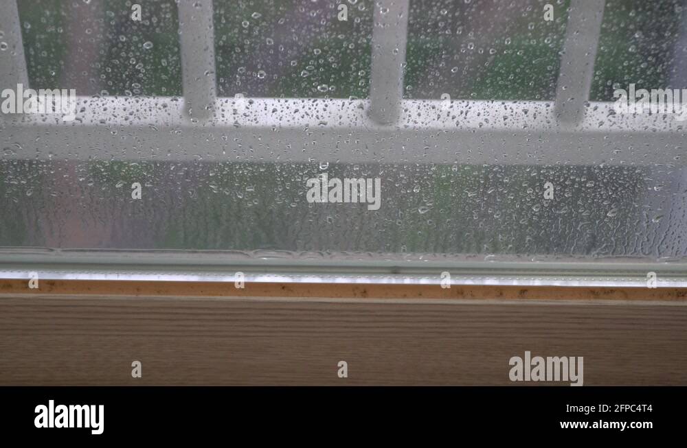 Raindrops Dripping On The Surface of Glass Window on blury background