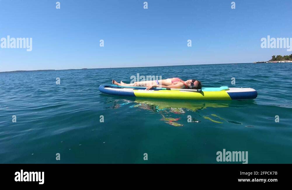 Sexy girl in bikini sunbathing on SUP. Lying on the paddle board Stock