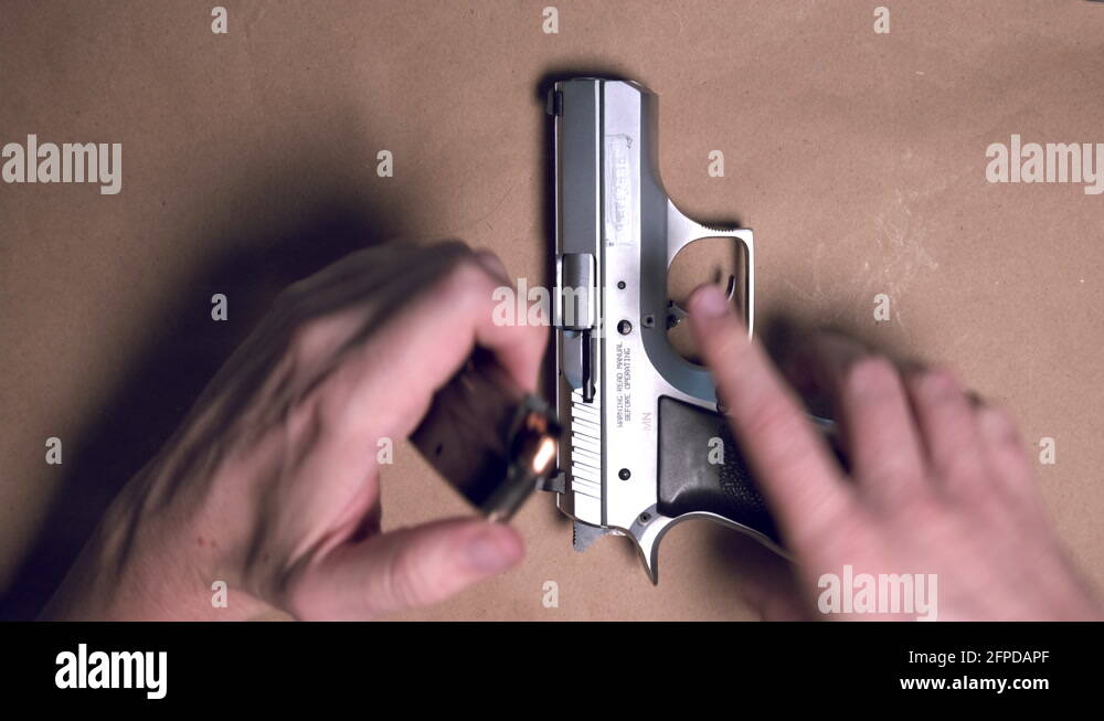 Top down shot of male hands loading 9mm pistol magazine and loading gun