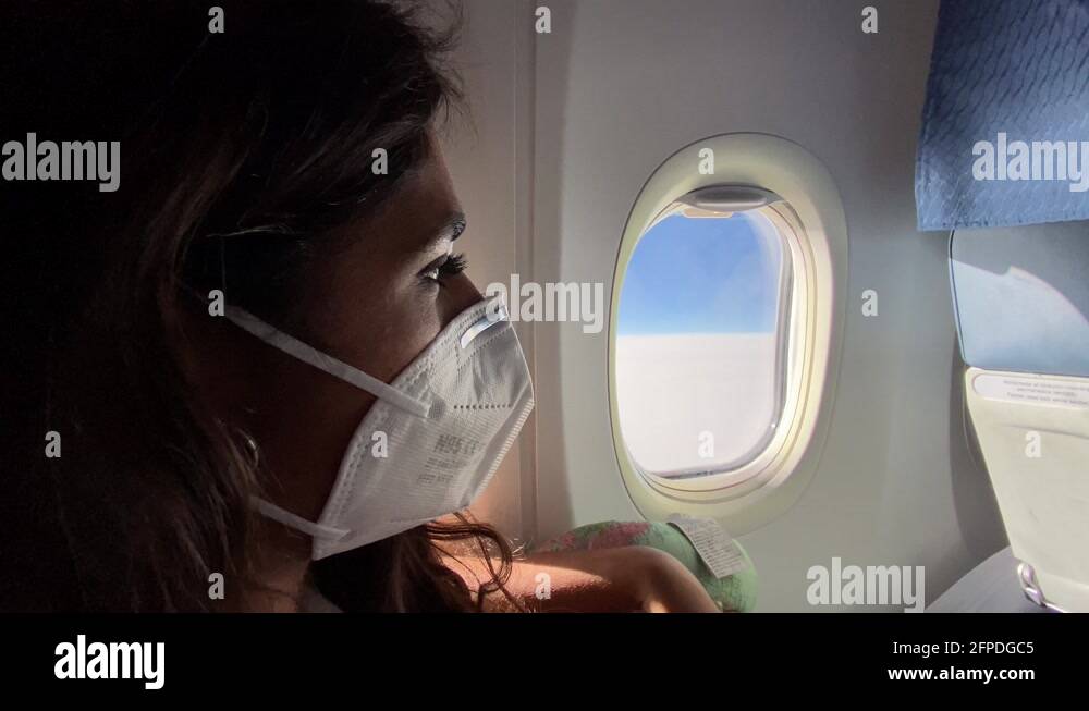 Woman wearing a face mask on a plane during the covid pandemic Stock