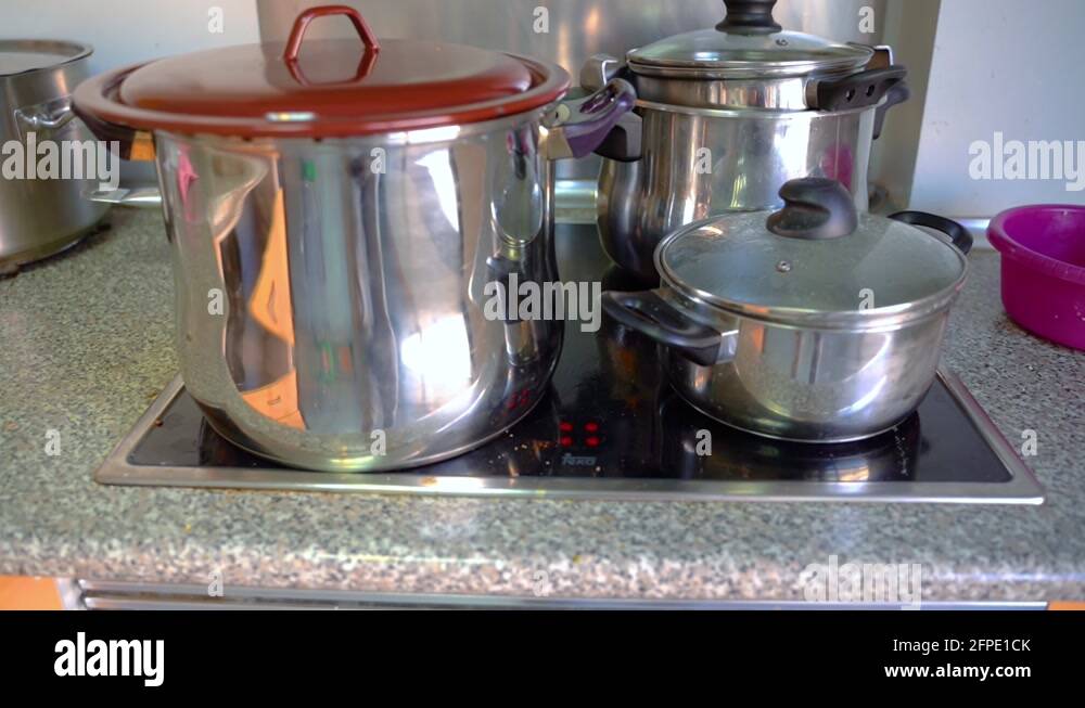Stainless Pots With Lids On An Induction Cooktop In The Kitchen close