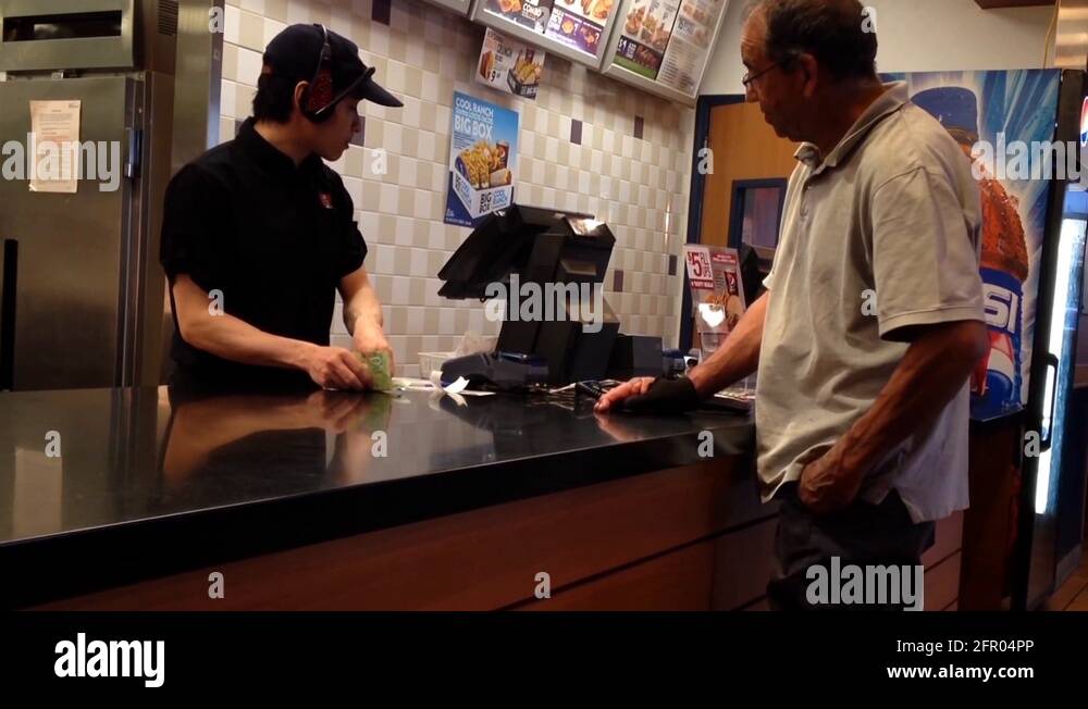 People ordering food and paying cash at KFC check out counter Stock