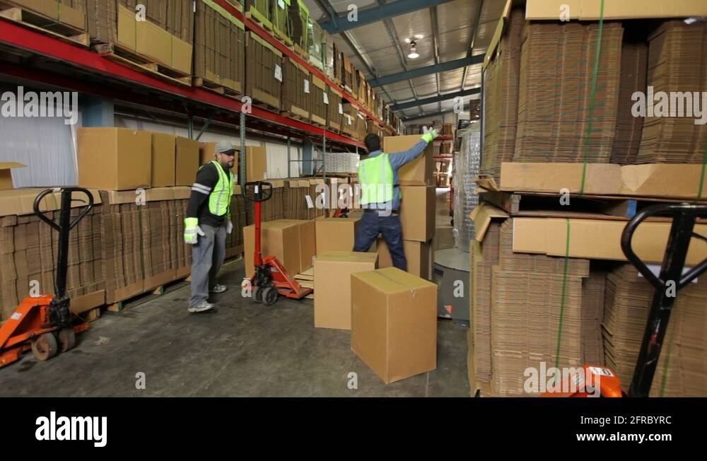 Two workers in shipping warehouse stacking boxes Stock Video Footage