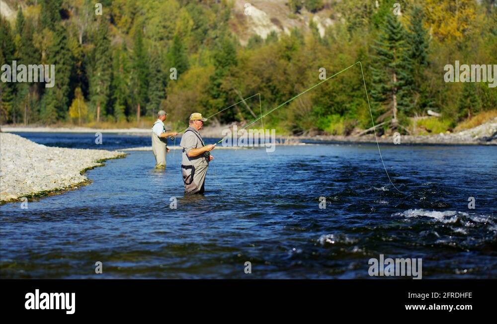 Fisherman fly fishing in Canadian river casting using rod and reel
