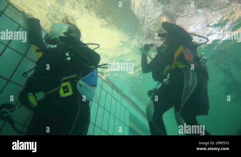 Girl in wetsuits with scuba rise above water in swimming pool Stock