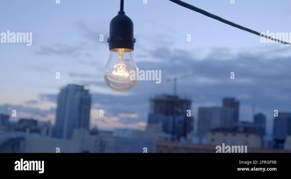 Light bulb hanging in front of Downtown Los Angeles skyline at sunset