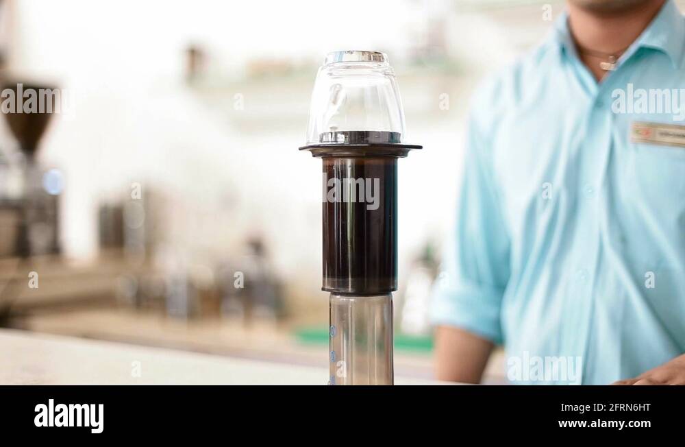 Indian man flips coffee apparatus to filter the coffee into the cup