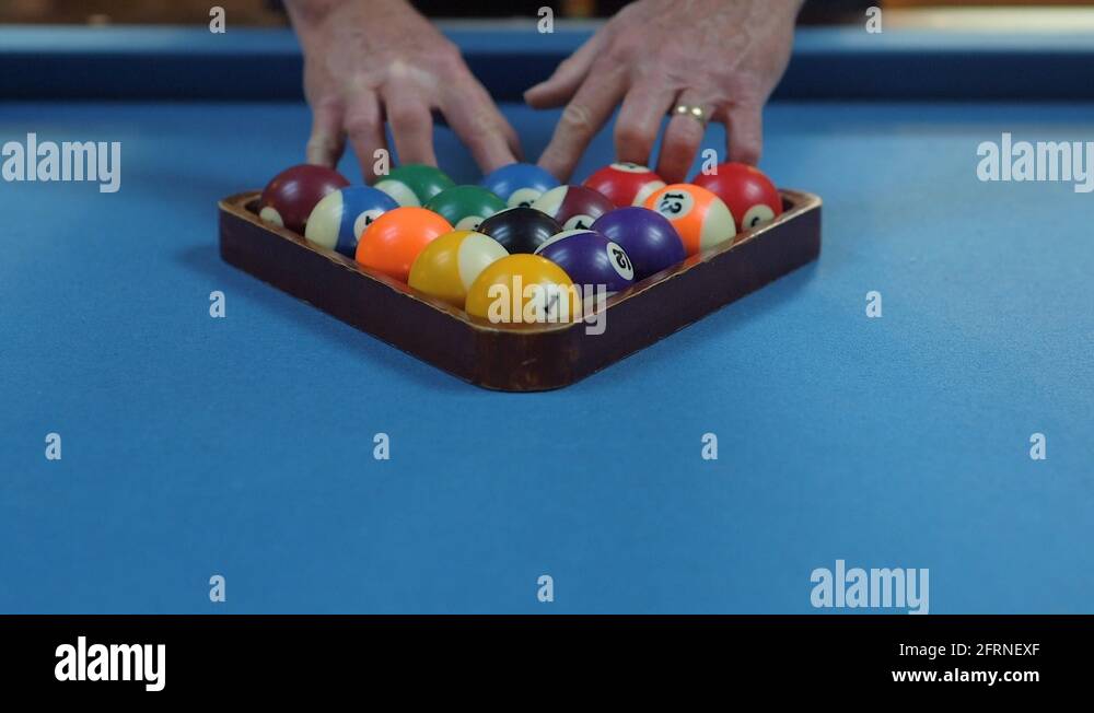 Man Racking Pool Balls in EightBall Formation on Blue Billiards Table