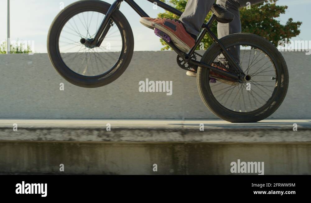 SLOW MOTION CLOSE UP Young bmx biker jumping ollie and wiring wheelie