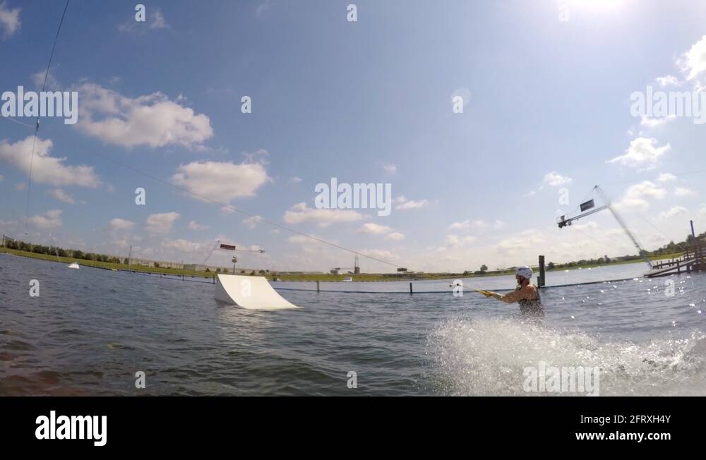 A man jumping his wakeboard off a ramp at a cable park Stock Video