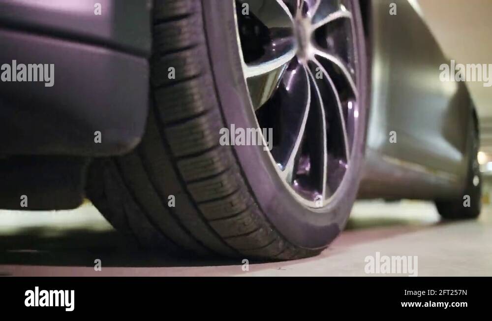 Wheel of car moving backward in parking, headlights illuminate, close