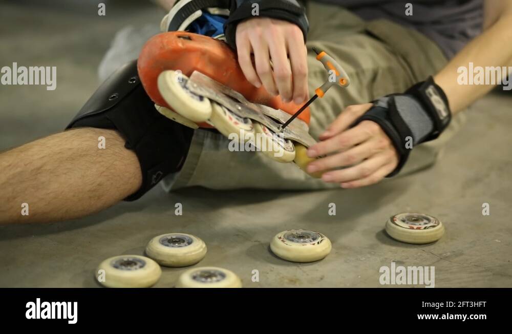 Guy on roller skates sitting and changing wheel in its skate Stock