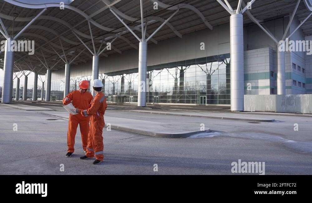 Construction workers in orange uniform and hardhats looking over plans ...