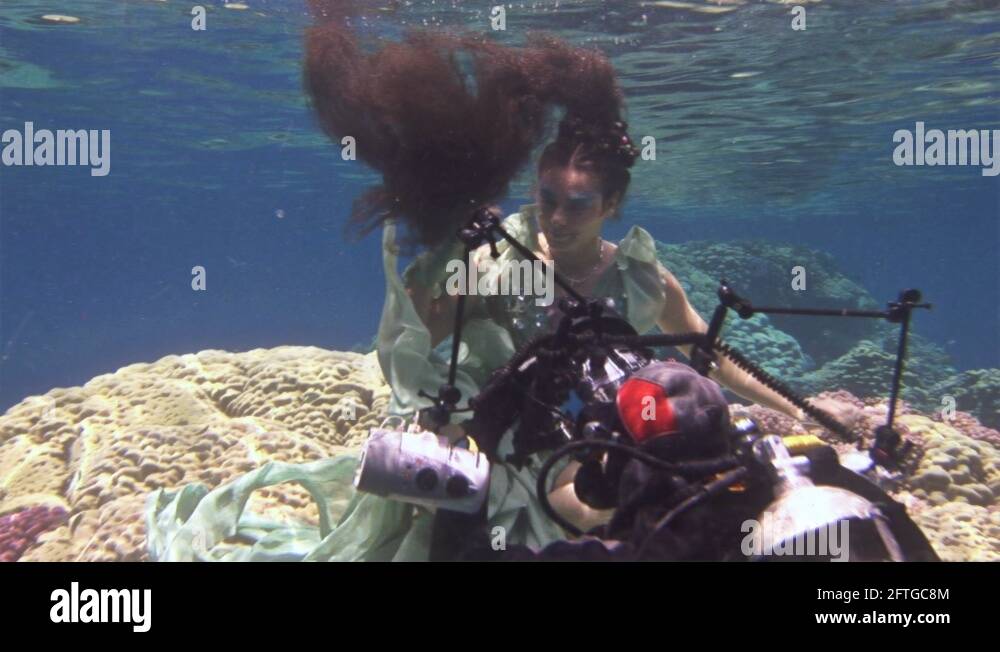 Underwater model free diver poses for camera on background of corals in