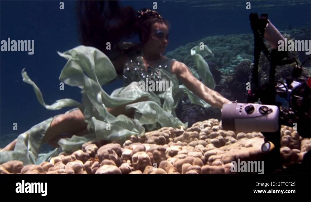 Underwater model free diver poses for camera on background of corals in