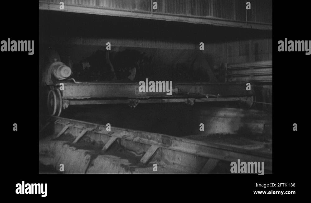 1940s hopper empties contents into blast furnace. Man rides truck on