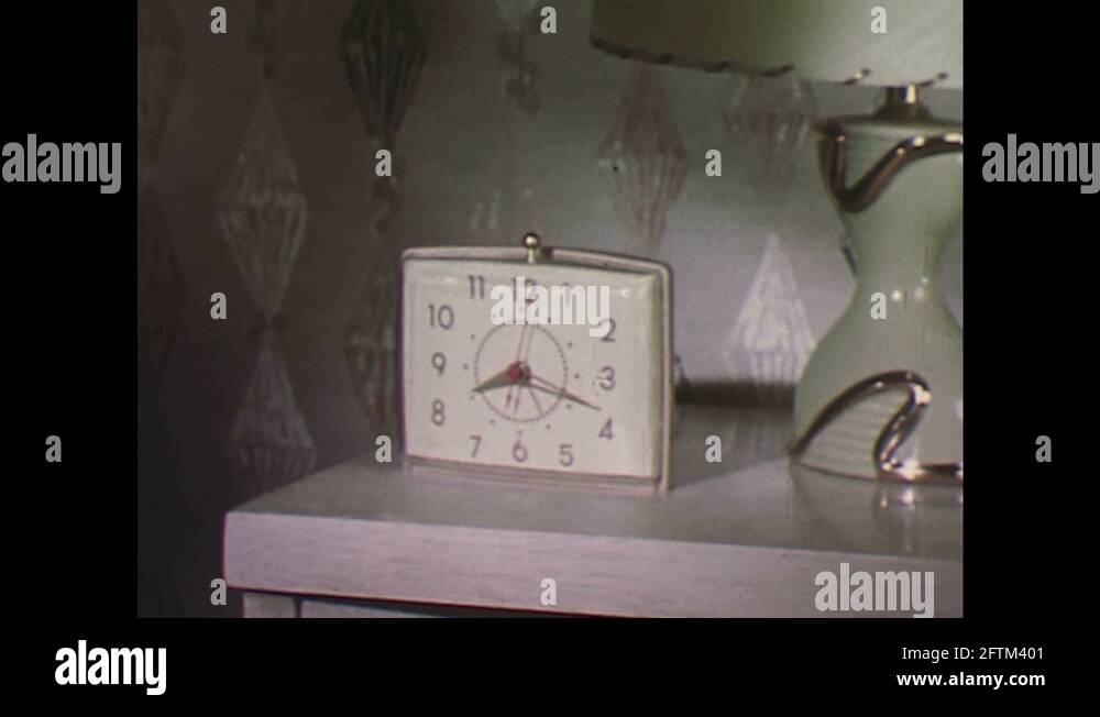 1960s Zoom in on alarm clock, clock changes color / Hand sets time on