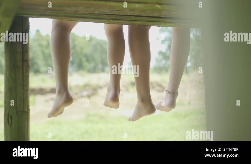 Brother and sister sitting side by side with feet dangling Stock Video