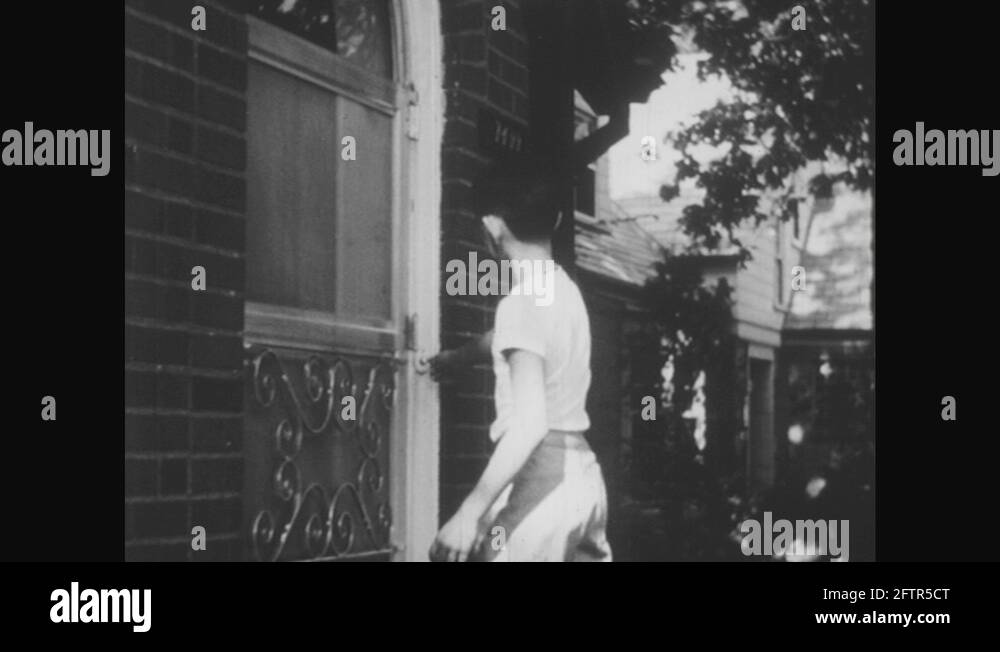 1950s UNITED STATES boy rings doorbell. Lady opens door. Boy points