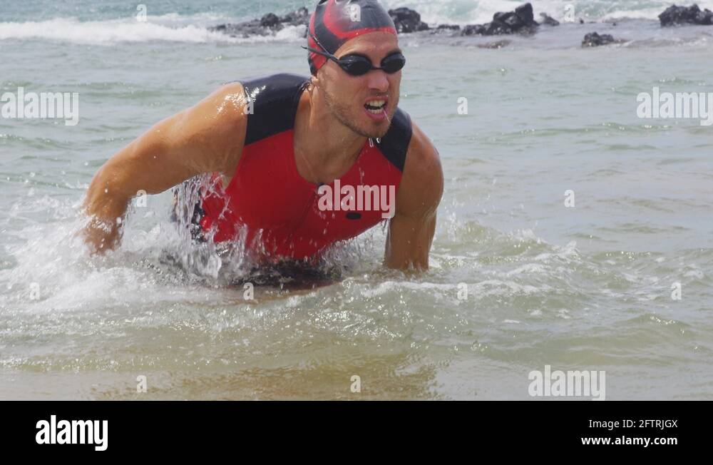 Triathlon swim male triathlete swimmer man running out of ocean after
