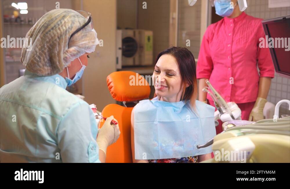Female dentist showing patient how to brush teeth. She using macet of