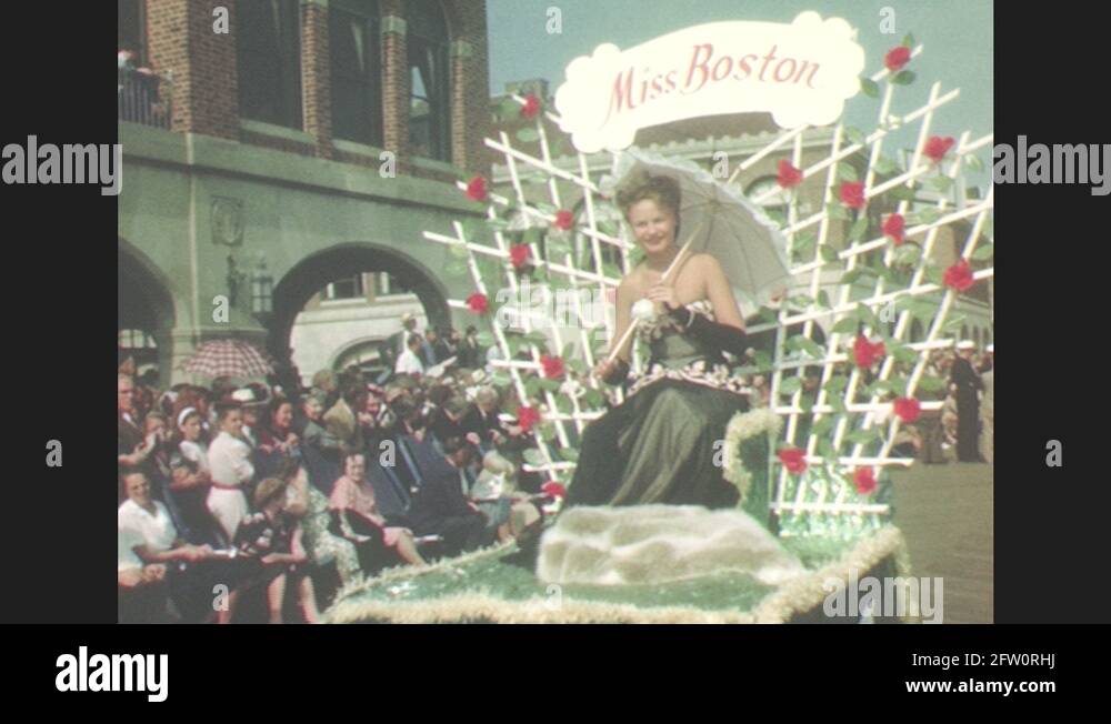 1940s Woman passes crowd on pageant float under umbrella. Marching