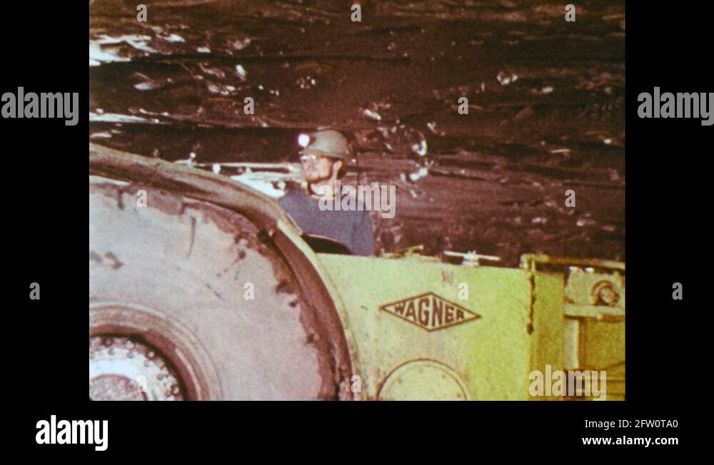 1970s: Industrial vehicles roll through mine. Miner inserts blasting ...