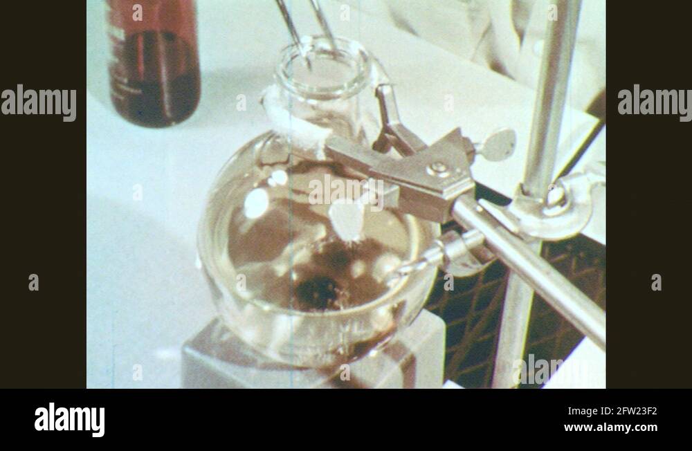 1960s Tweezers drop plastic bar into flask. Hands turn on