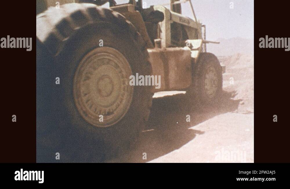 1970s Tractor pulls large hopper, drops dirt out of bottom of hopper