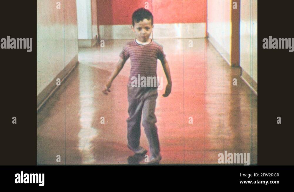 1970s Feet with toes turned in walking. Boy walking down hallway with