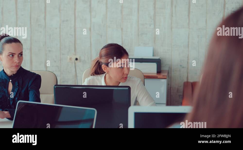 Asian girl behind laptops in the office communicates with colleagues ...