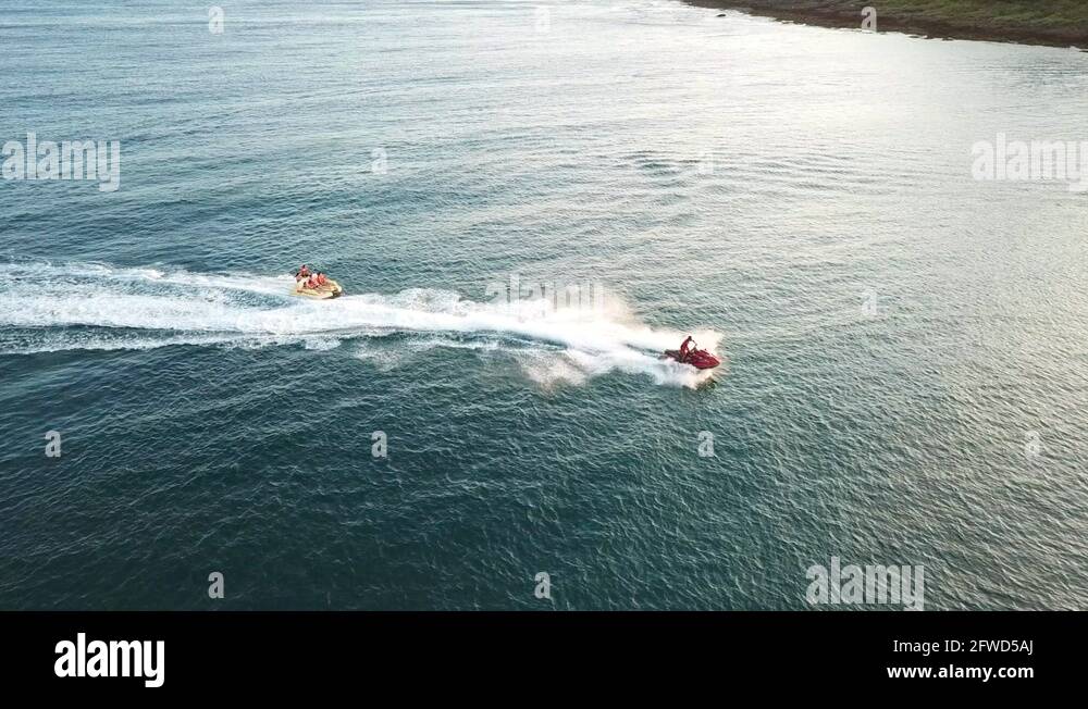 Jet ski towing a raft of people across the sea towards the beach of
