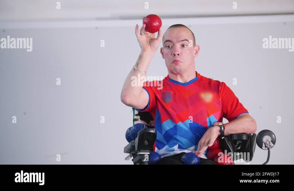 A disabled man in a wheelchair. Throwing a red little ball in the air