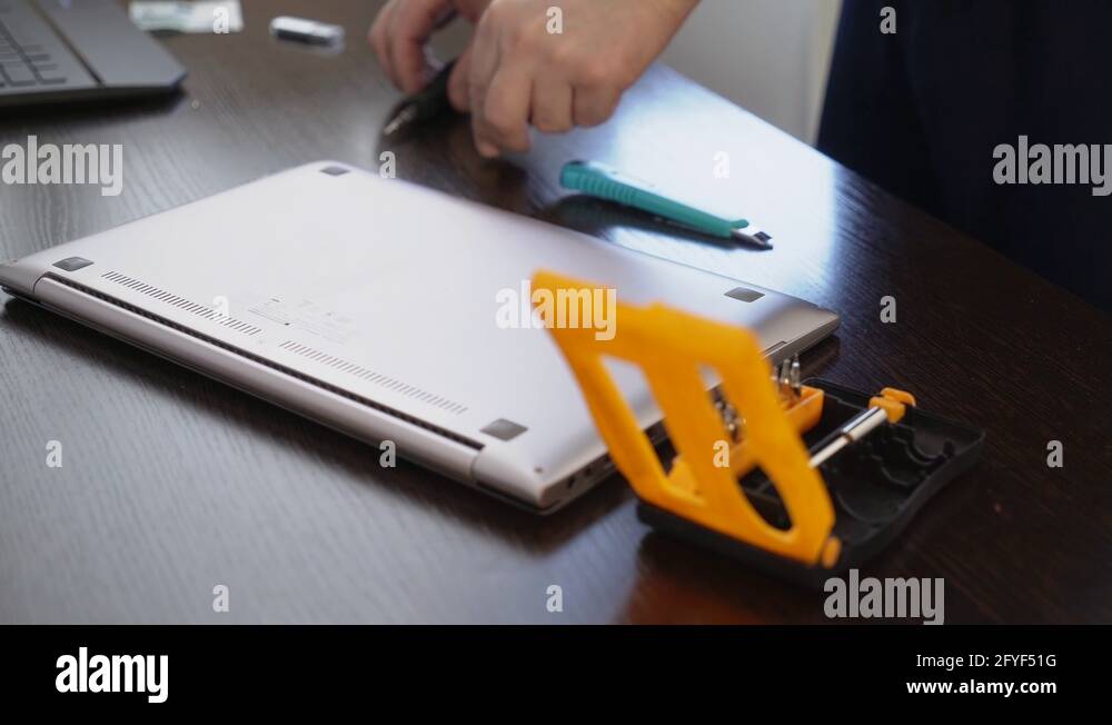 The wizard uses a screwdriver to unscrew the screw from the laptop